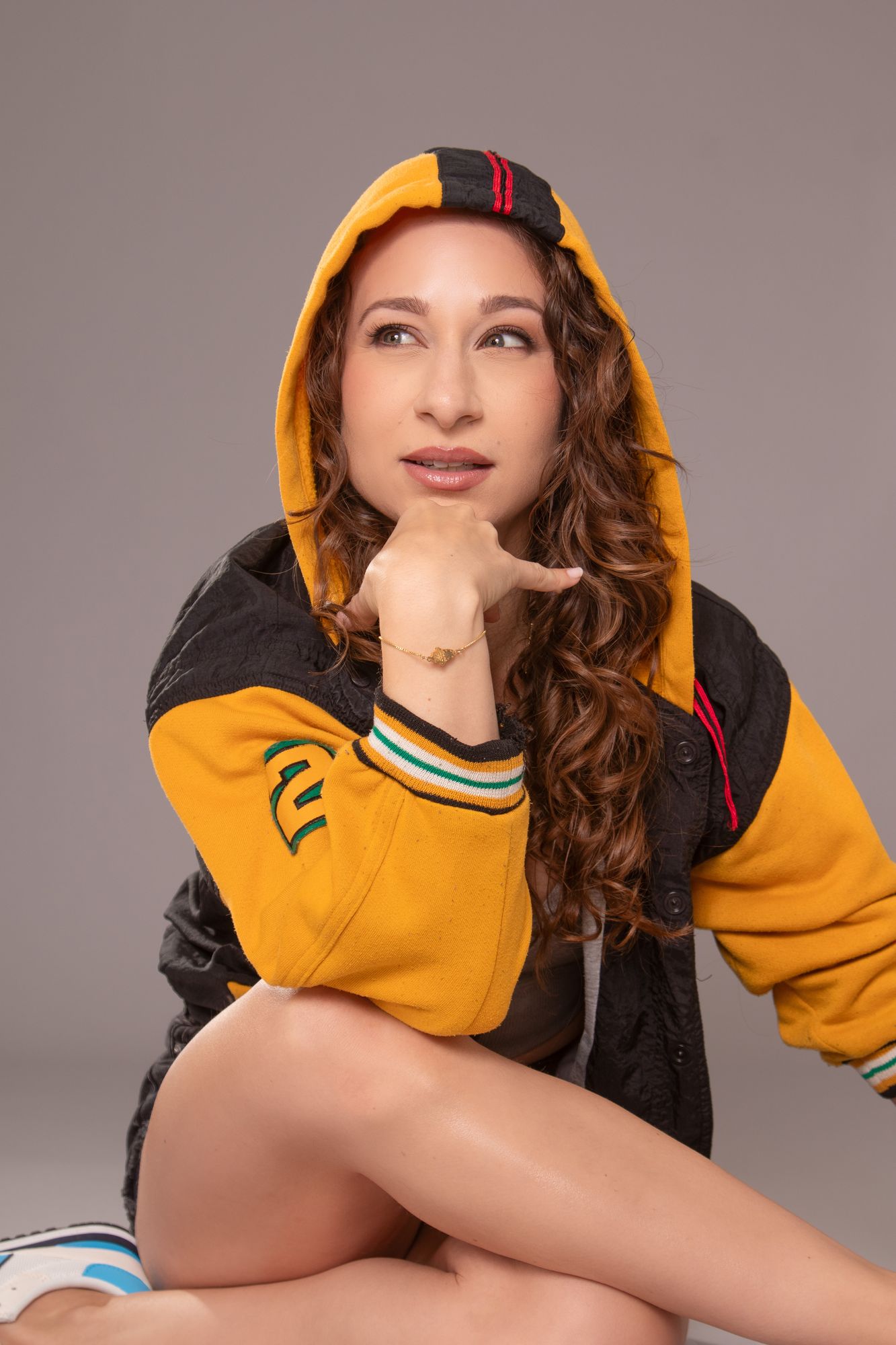 Galit in a yellow hooded jacket, chin on her hand, looking off to one side