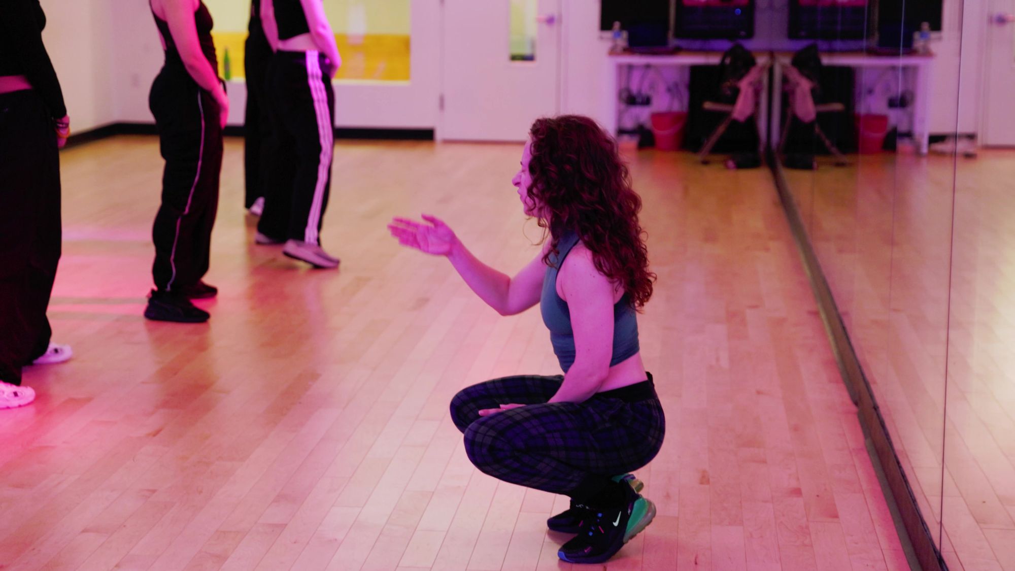 Galit crouched by the mirror, working one dancer through a phrase