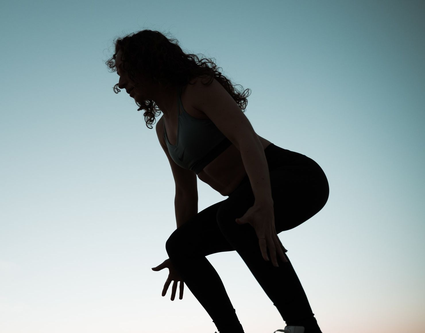 Galit in silhouette, crouched low, against a pale evening sky
