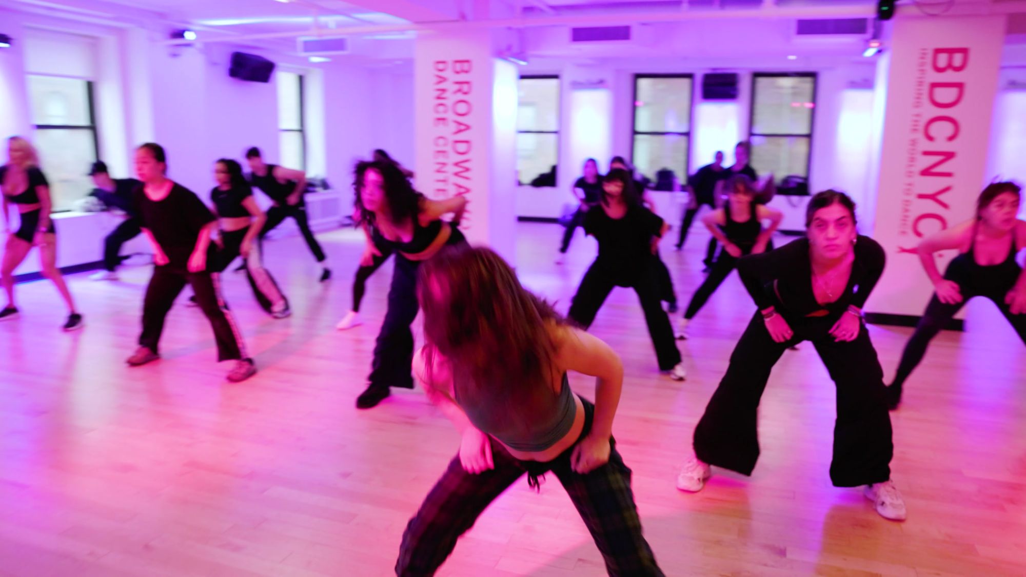Galit at the front of a full room at Broadway Dance Center, everyone low in the same stance behind her